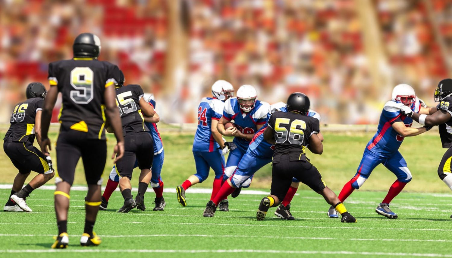 A group of high school football players compete on the field.