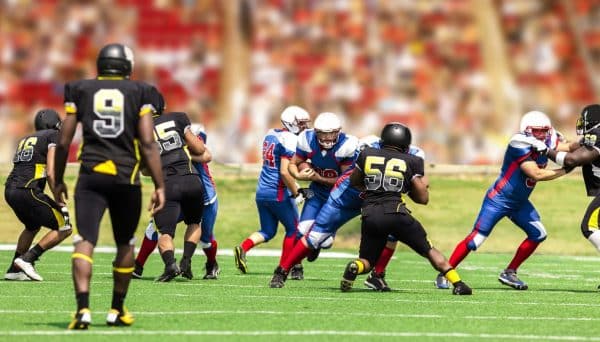 A group of high school football players compete on the field.