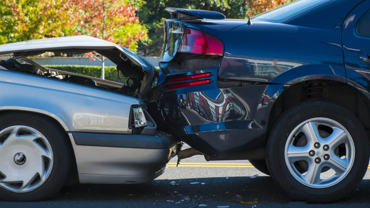 A silver car has rear-ended a black car, with significant damage to both vehicles.